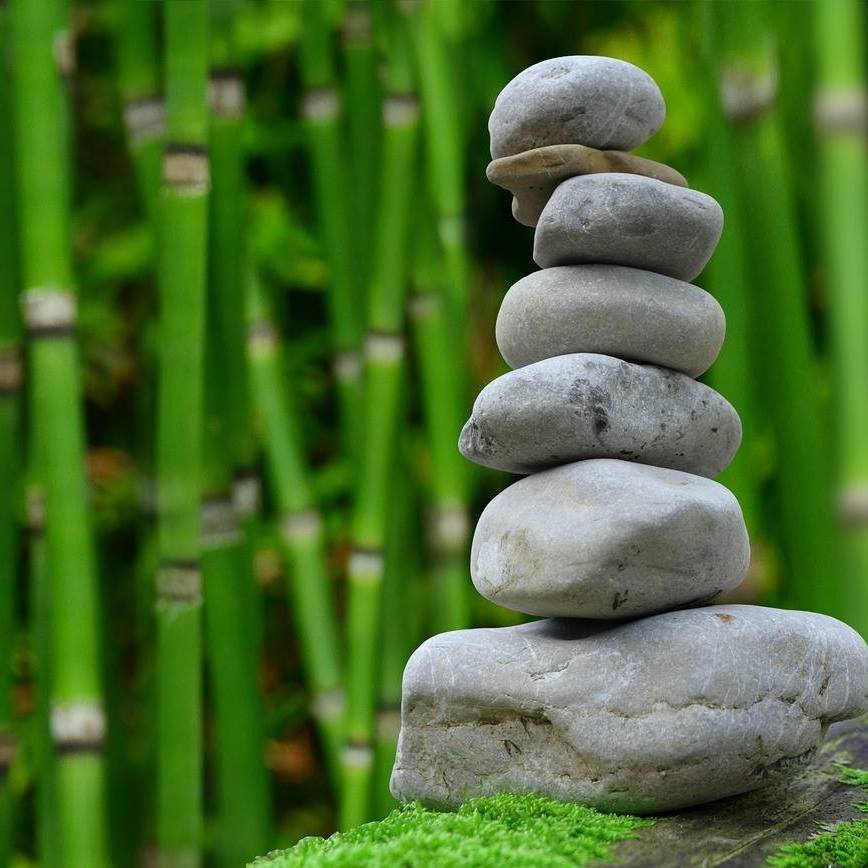 Kivistä tehty patsas. Kivet pinottu päällekkäin. Taustalla bamburuokoja.